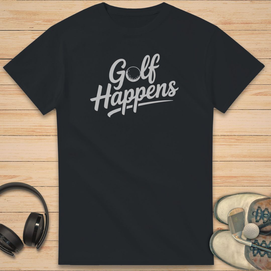 Golf Happens T-Shirt in Black on a light wooden floor lying next to headphones and golf shoes.
