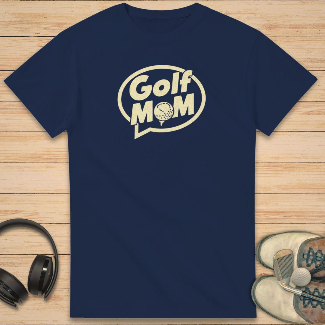 Golf Mom T-Shirt in Navy on a light wooden floor lying next to headphones and golf shoes.