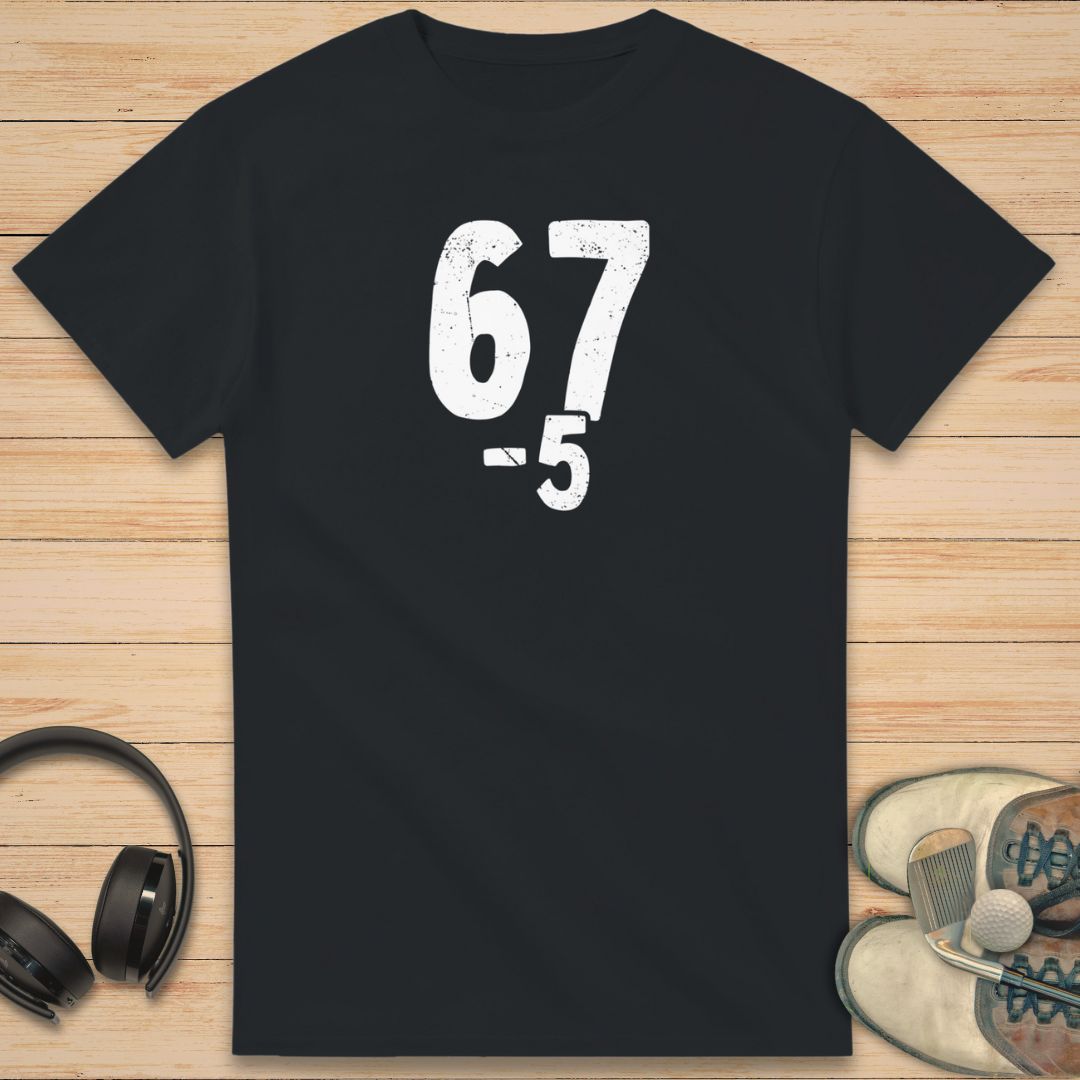 67 5 Under T-Shirt in Black on a light wooden floor lying next to headphones and golf shoes.