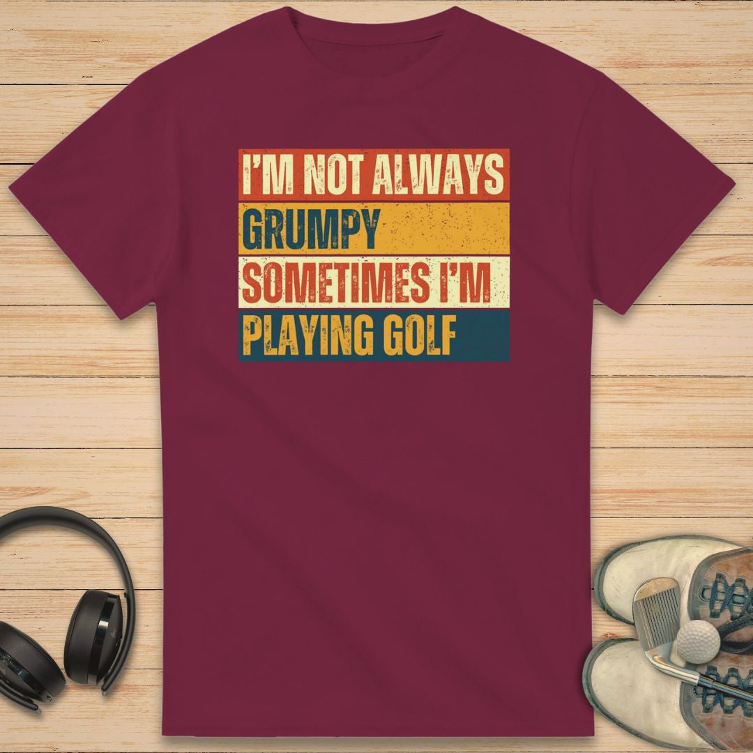 Grumpy Vintage T-Shirt in Maroon on a light wooden floor lying next to headphones and golf shoes.