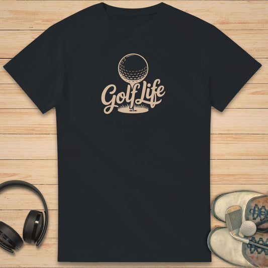 Golf Life T-Shirt in Black on a light wooden floor lying next to headphones and golf shoes.