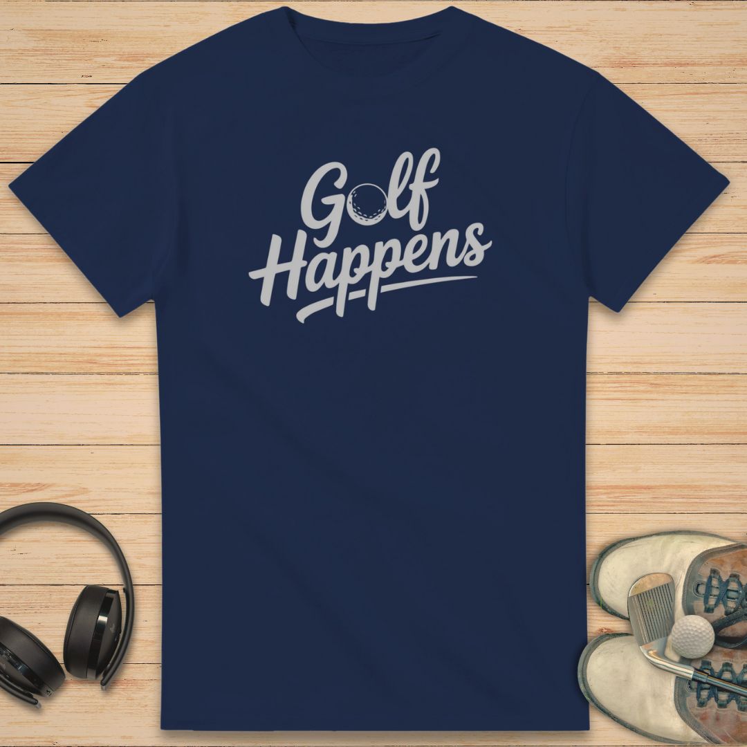 Golf Happens T-Shirt in Navy on a light wooden floor lying next to headphones and golf shoes.