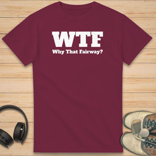 WTF T-Shirt in Maroon on a light wooden floor lying next to headphones and golf shoes.