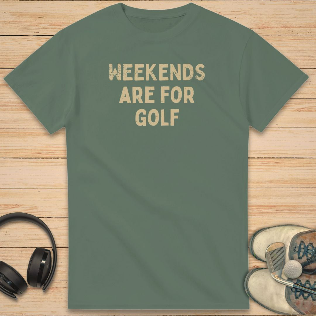 Weekends T-Shirt in Military Green on a light wooden floor lying next to headphones and golf shoes.