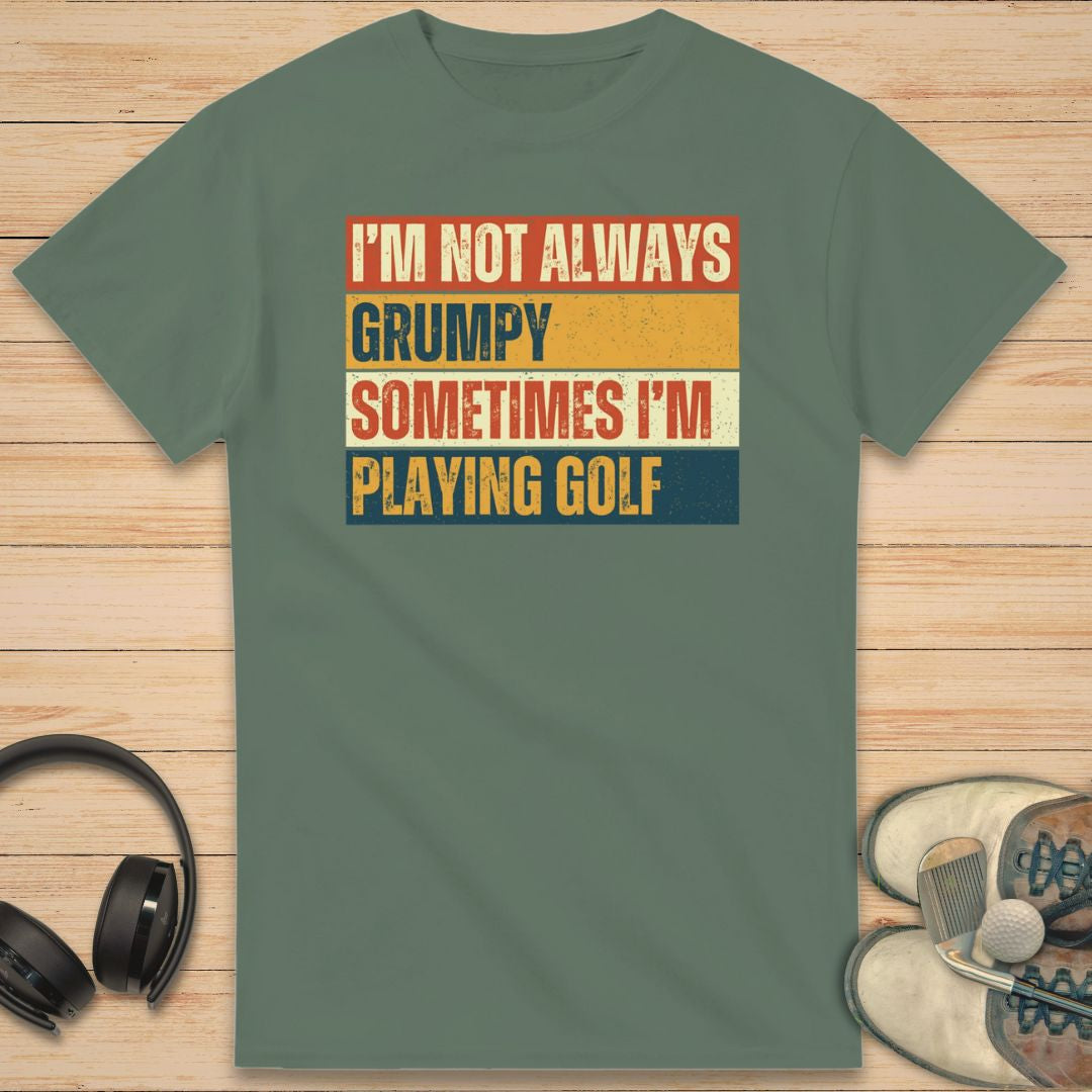 Grumpy Vintage T-Shirt in Military Green on a light wooden floor lying next to headphones and golf shoes.