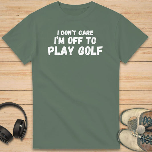 Don't Care T-Shirt in Military Green on a light wooden floor lying next to headphones and golf shoes.