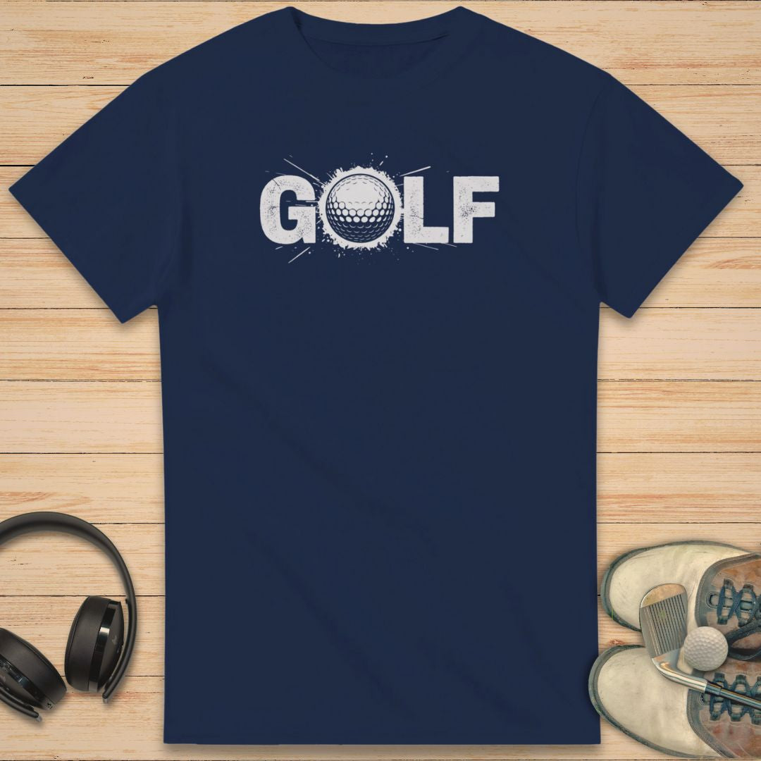 Golf Crash T-Shirt in Navy on a light wooden floor lying next to headphones and golf shoes.