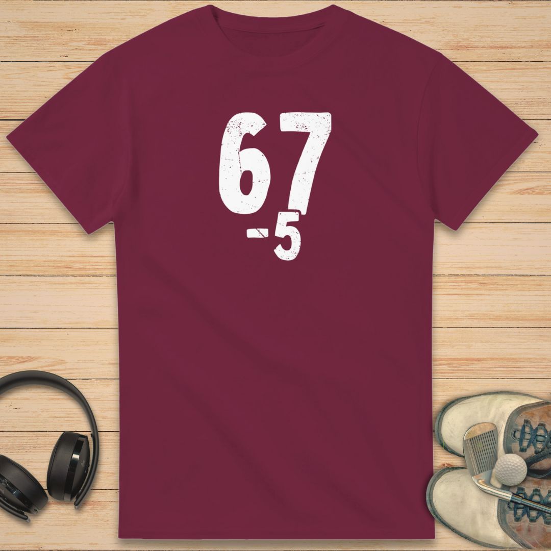67 5 Under T-Shirt in Maroon on a light wooden floor lying next to headphones and golf shoes.