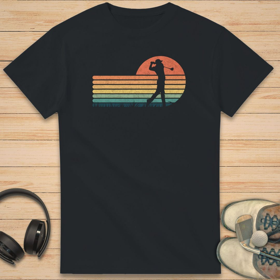 Vintage Golfer T-Shirt in Black on a light wooden floor lying next to headphones and golf shoes.