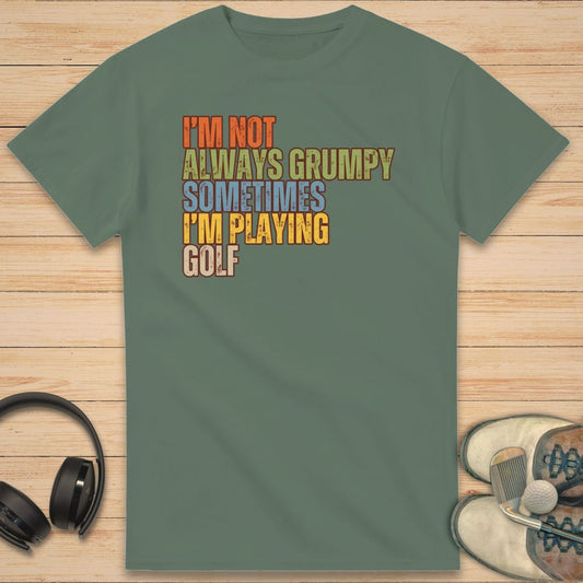 Grumpy Classic T-Shirt in Military Green on a light wooden floor lying next to headphones and golf shoes.