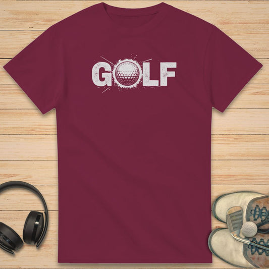 Golf Crash T-Shirt in Maroon on a light wooden floor lying next to headphones and golf shoes.