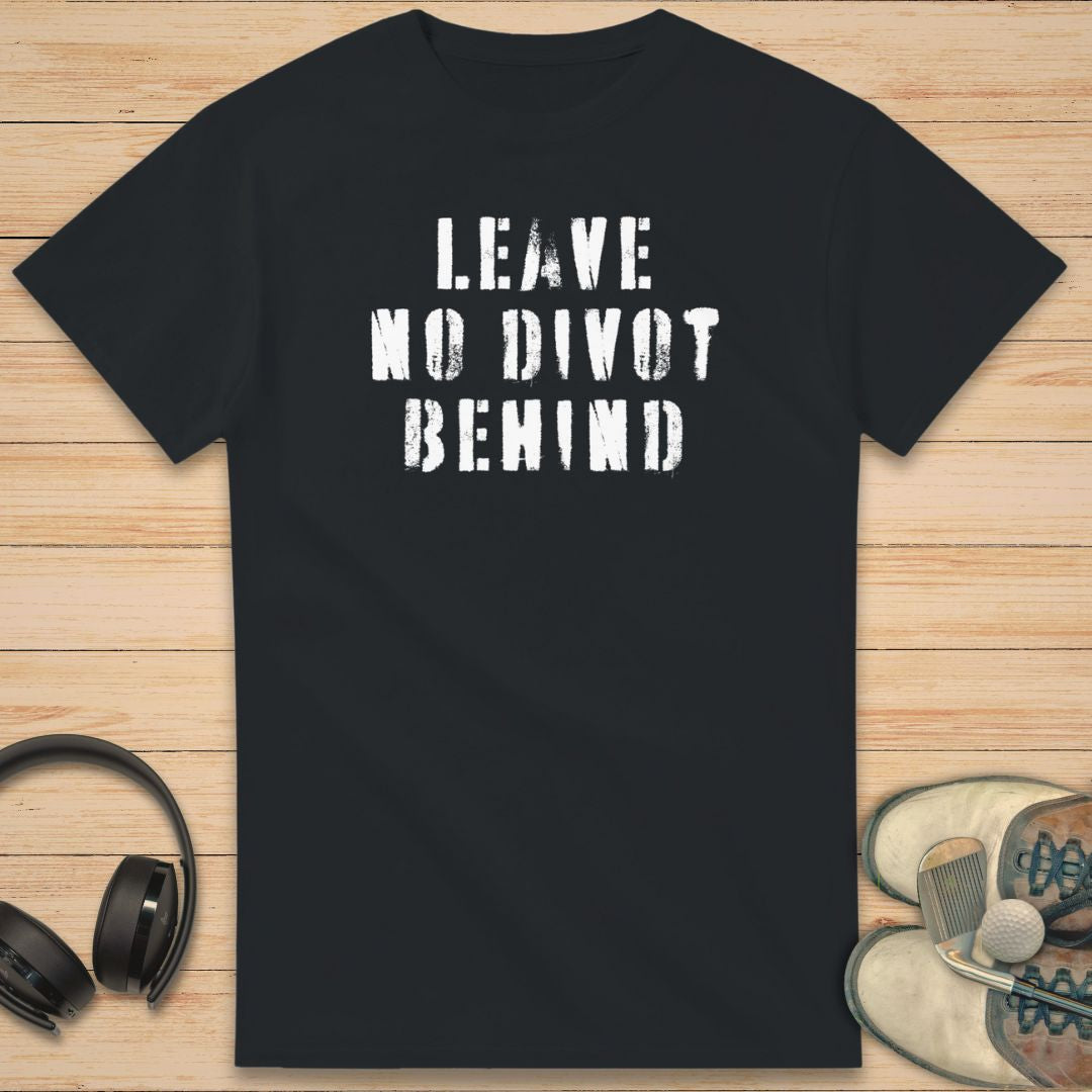 No Divot T-Shirt in Black on a light wooden floor lying next to headphones and golf shoes.