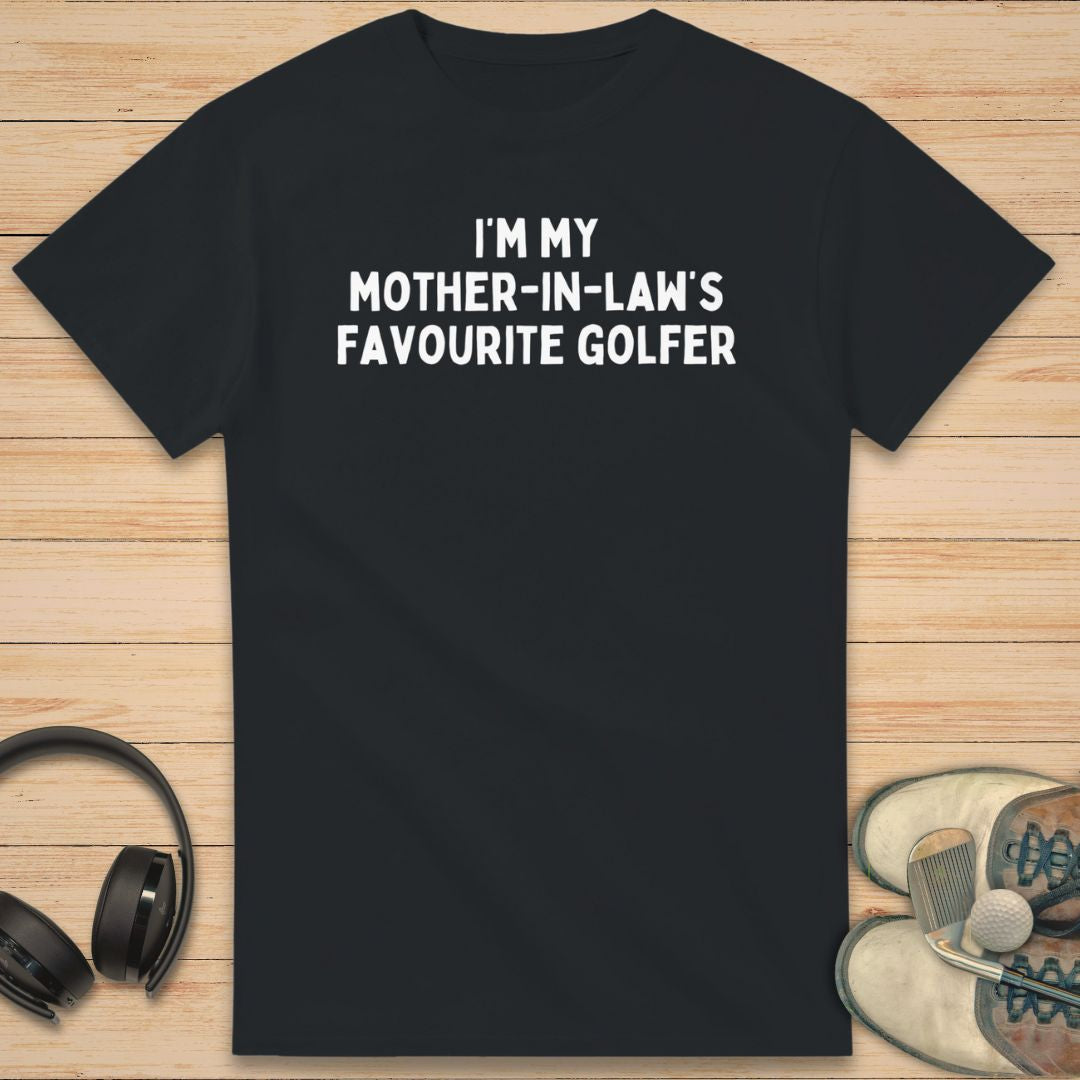 Mother-In-Law T-Shirt in Black on a light wooden floor lying next to headphones and golf shoes.