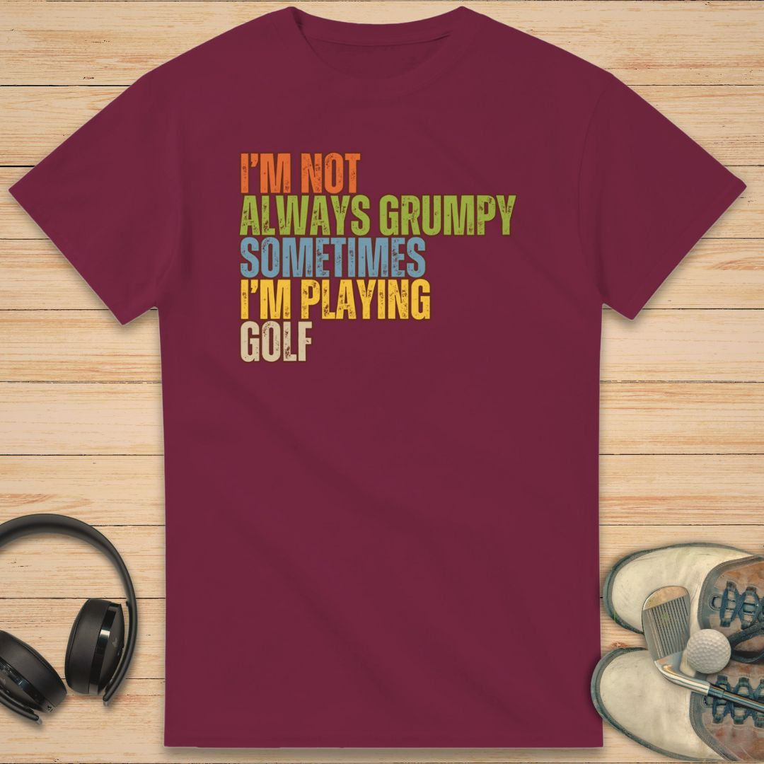 Grumpy Classic T-Shirt in Maroon on a light wooden floor lying next to headphones and golf shoes.