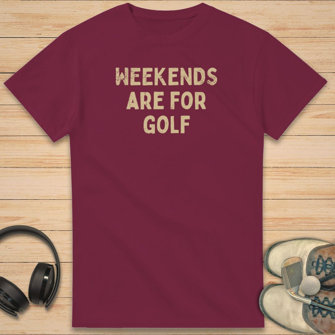 Weekends T-Shirt in Maroon on a light wooden floor lying next to headphones and golf shoes.