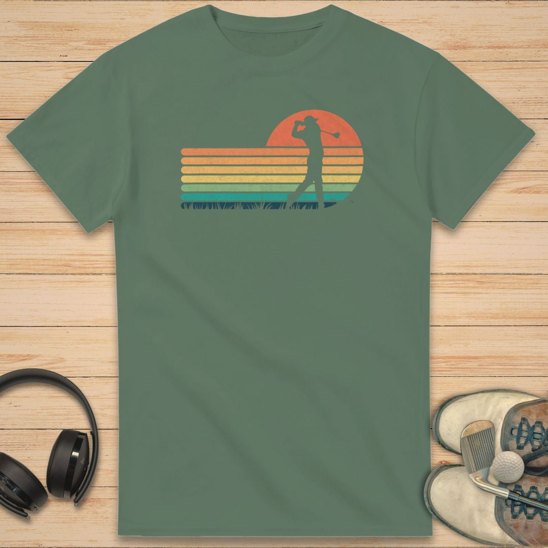 Vintage Golfer T-Shirt in Military Green on a light wooden floor lying next to headphones and golf shoes.