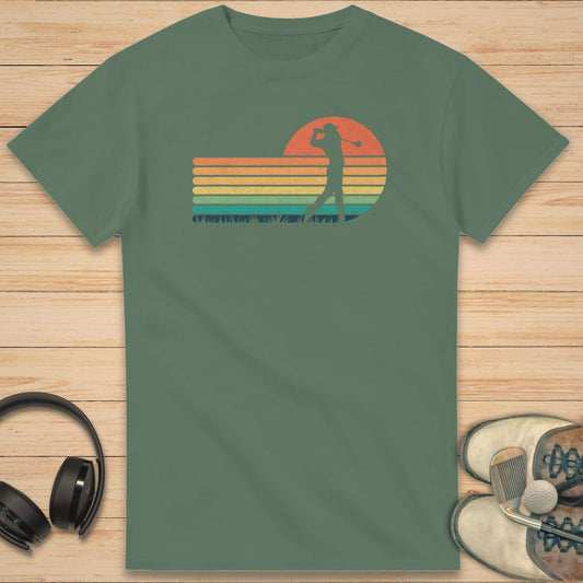 Vintage Golfer T-Shirt in Military Green on a light wooden floor lying next to headphones and golf shoes.
