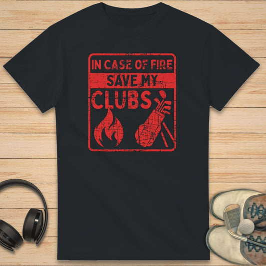 Save My Clubs T-Shirt in Black on a light wooden floor lying next to headphones and golf shoes.