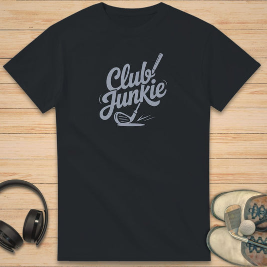 Club Junkie T-Shirt in Black on a light wooden floor lying next to headphones and golf shoes.