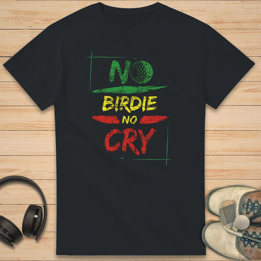 No Birdie No Cry T-Shirt in Black on a light wooden floor lying next to headphones and golf shoes.