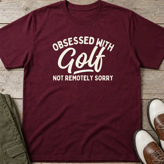 Obsessed With Golf T-Shirt in Maroon lying on a plain floor. T-shirt is a unisex cut and 100 per cent cotton.