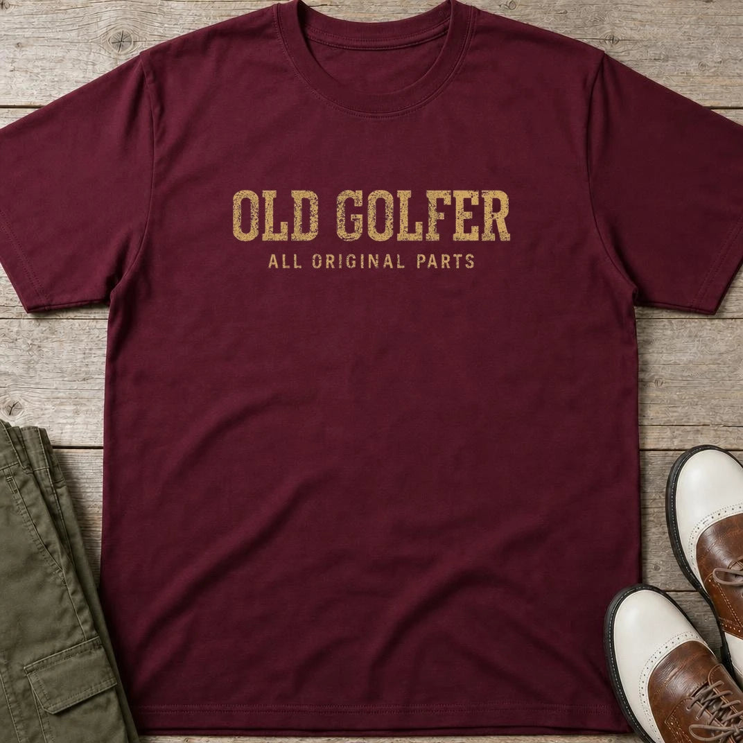 Old Golfer II T-Shirt in Maroon lying on a plain floor. T-shirt is a unisex cut and 100 per cent cotton.