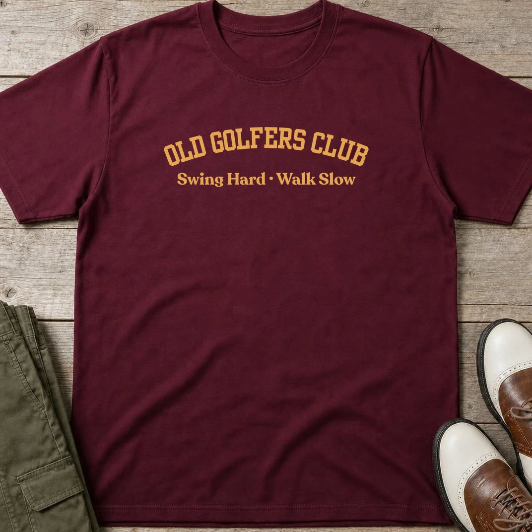 Old Golfers T-Shirt in Maroon lying on a plain floor. T-shirt is a unisex cut and 100 per cent cotton.