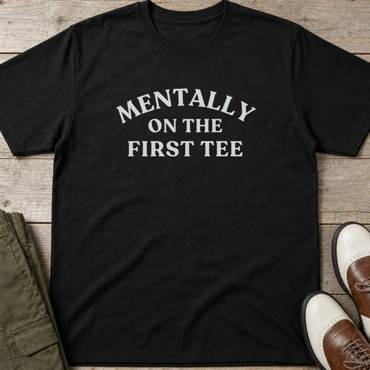 On The First Tee T-Shirt in Black lying on a plain floor. T-shirt is a unisex cut and 100 per cent cotton.