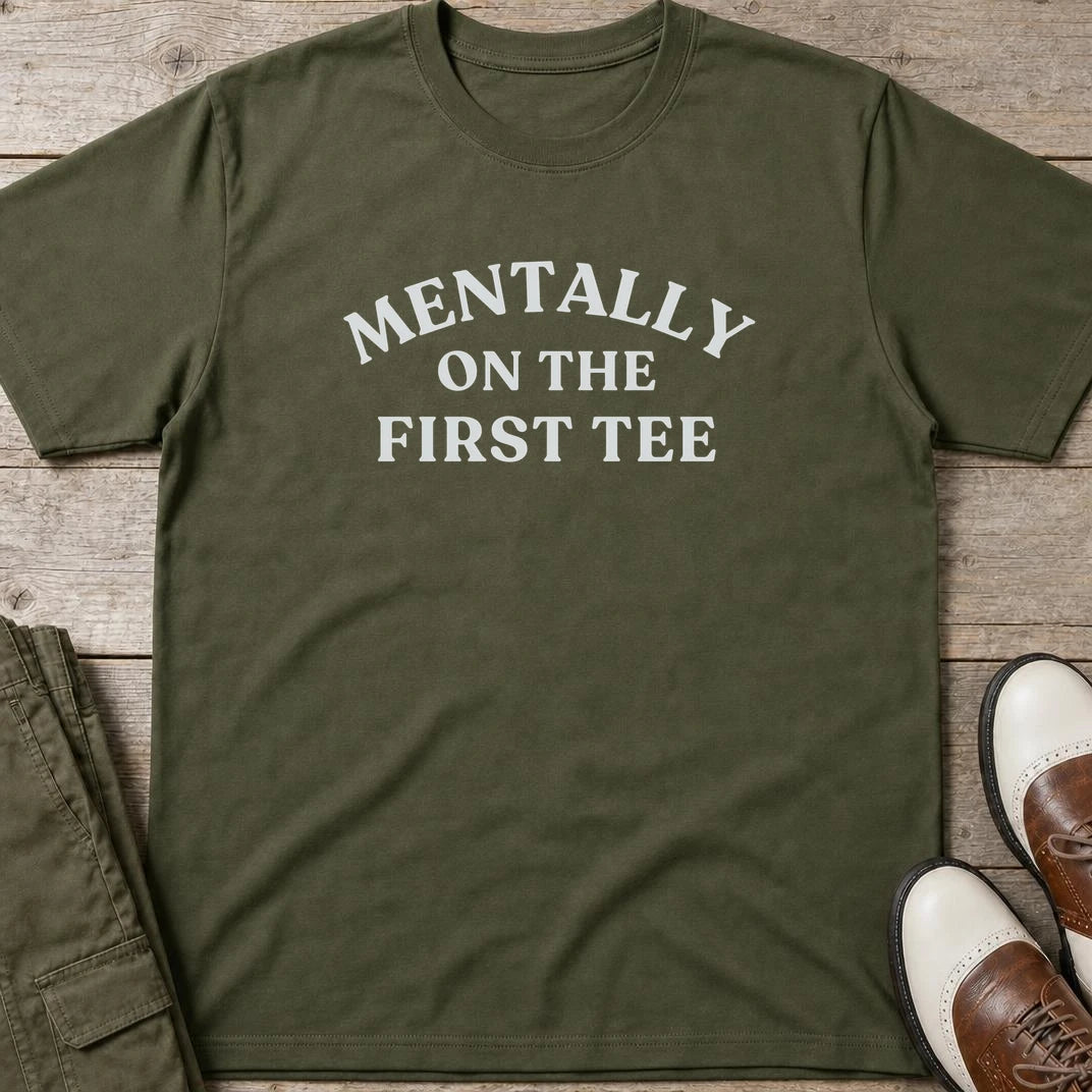 On The First Tee T-Shirt in Military Green lying on a plain floor. T-shirt is a unisex cut and 100 per cent cotton.