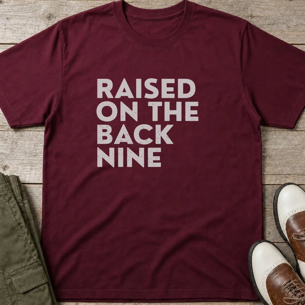 Raised On T-Shirt in Maroon lying on a plain floor. T-shirt is a unisex cut and 100 per cent cotton.