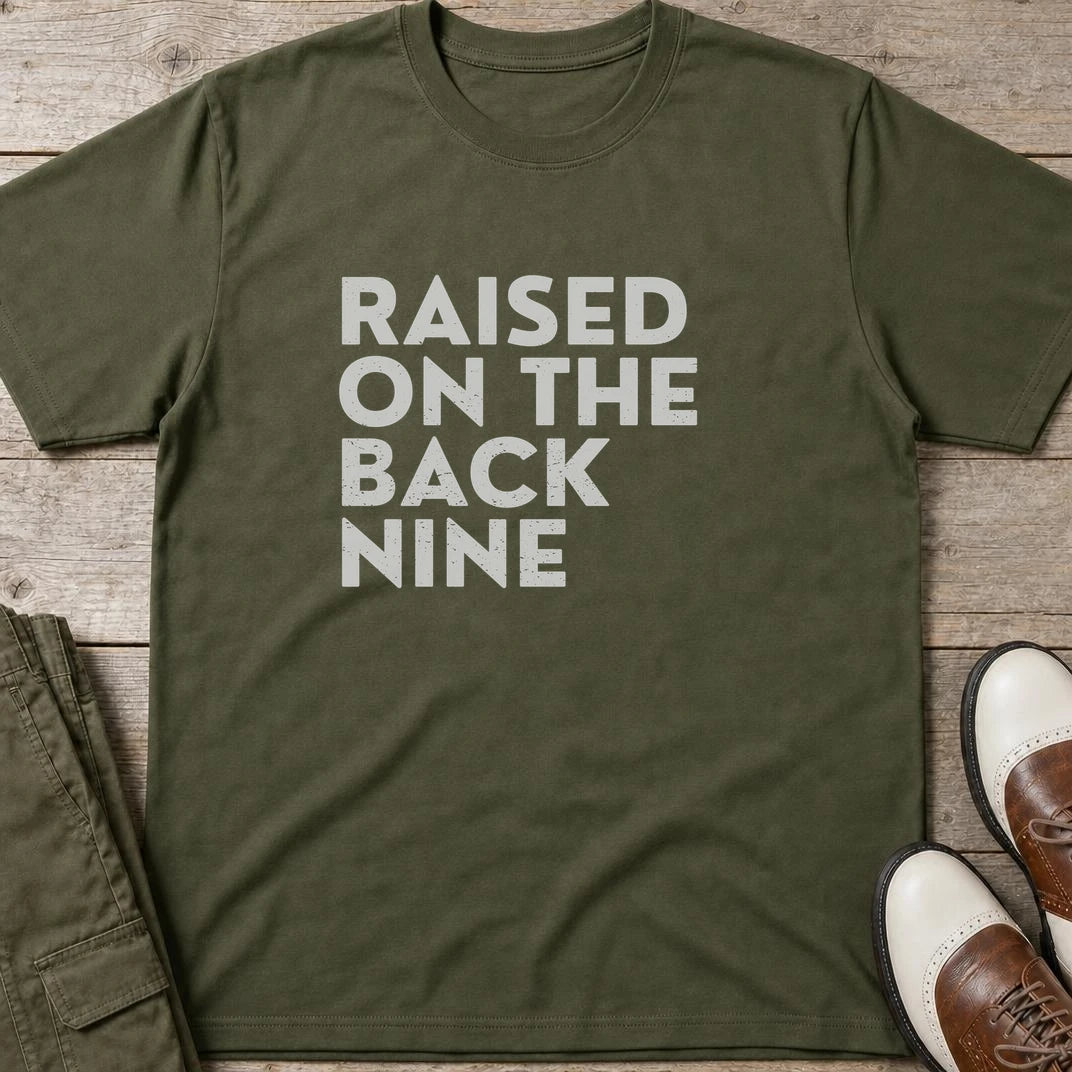 Raised On T-Shirt in Military Green lying on a plain floor. T-shirt is a unisex cut and 100 per cent cotton.