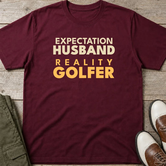 Reality Golfer T-Shirt in Maroon lying on a plain floor. T-shirt is a unisex cut and 100 per cent cotton.