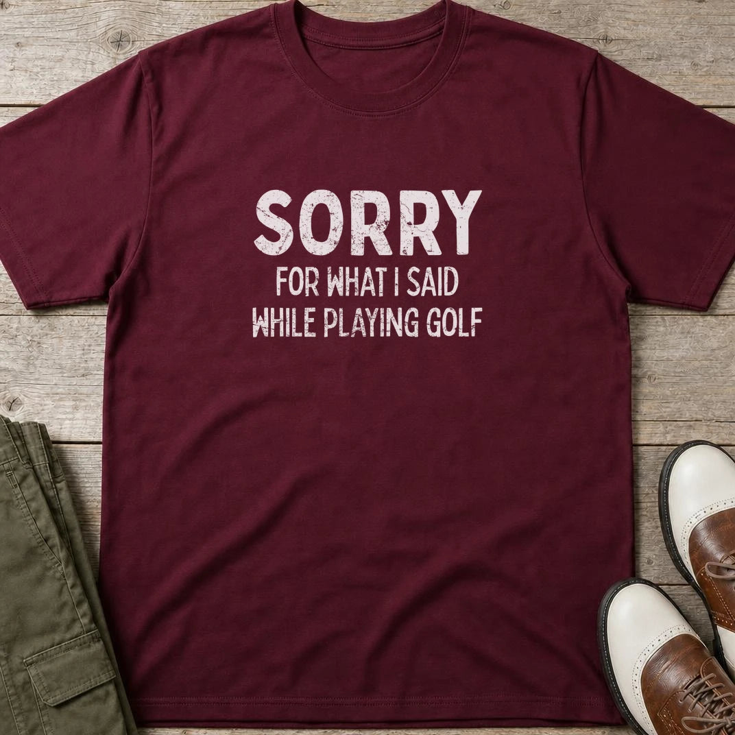Sorry T-Shirt in Maroon lying on a plain floor. T-shirt is a unisex cut and 100 per cent cotton.