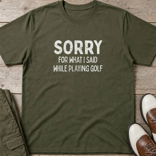 Sorry T-Shirt in Military Green lying on a plain floor. T-shirt is a unisex cut and 100 per cent cotton.