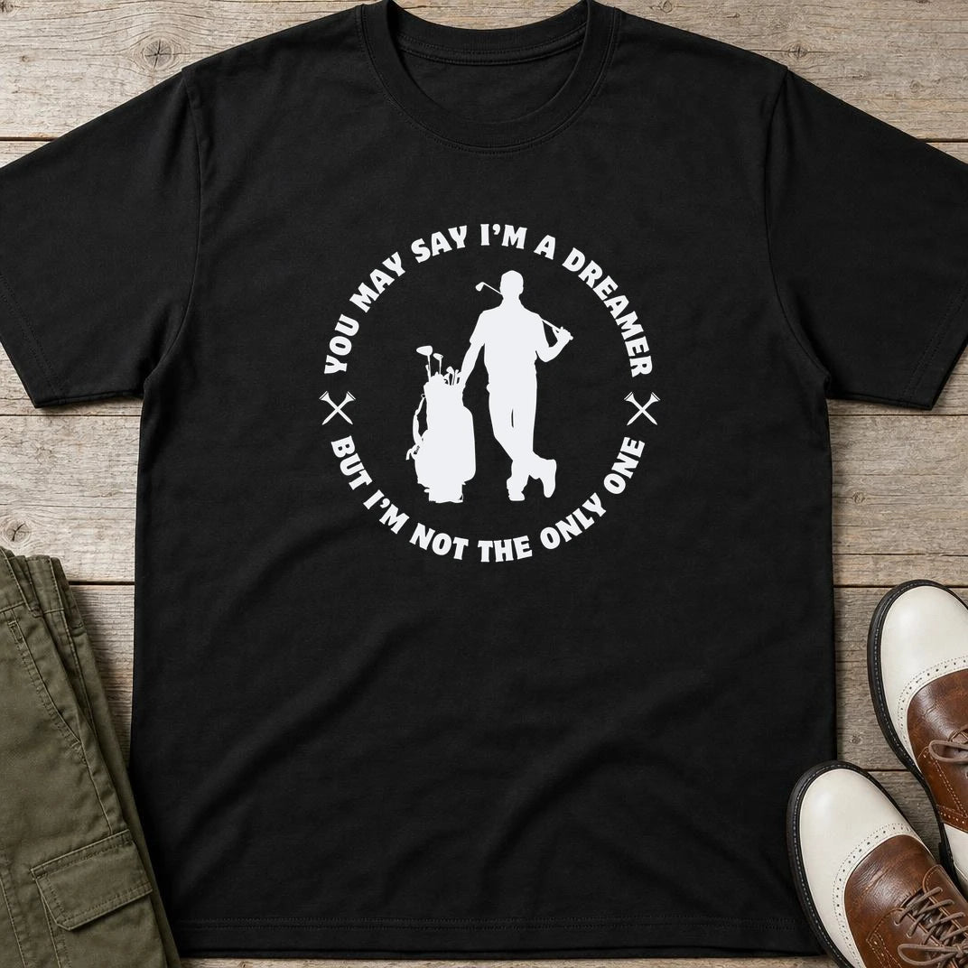 You May Say I'm A Dreamer T-Shirt in Black lying on a plain floor. T-shirt is a unisex cut and 100 per cent cotton.