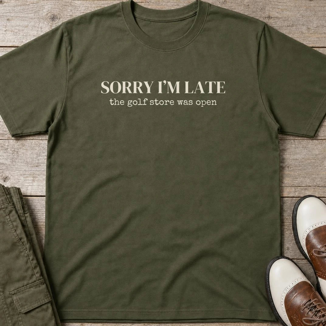 Sorry I'm Late T-Shirt in Military Green lying on a plain floor. T-shirt is a unisex cut and 100 per cent cotton.