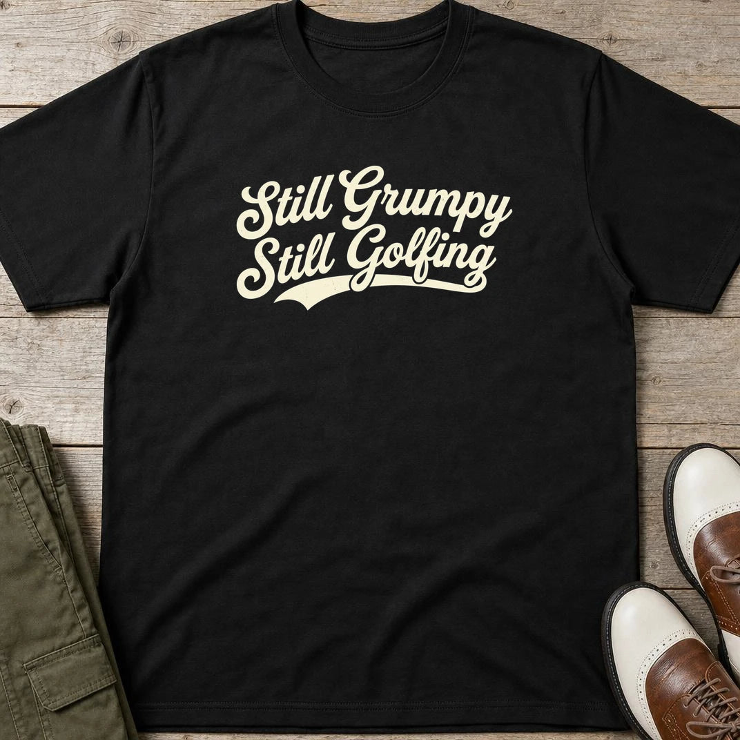 Still Grumpy T-Shirt in Black lying on a plain floor. T-shirt is a unisex cut and 100 per cent cotton.