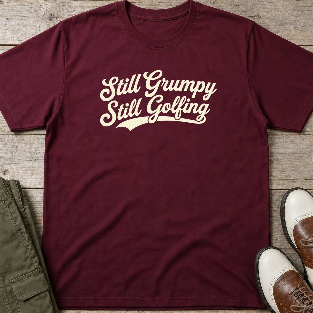 Still Grumpy T-Shirt in Maroon lying on a plain floor. T-shirt is a unisex cut and 100 per cent cotton.