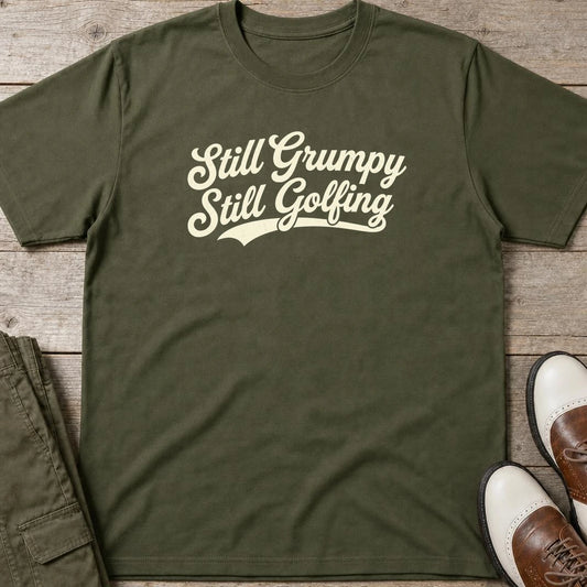 Still Grumpy T-Shirt in Military Green lying on a plain floor. T-shirt is a unisex cut and 100 per cent cotton.
