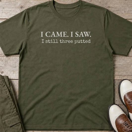 Still Three Putted T-Shirt in Military Green lying on a plain floor. T-shirt is a unisex cut and 100 per cent cotton.
