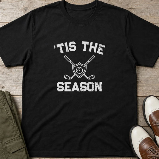 'Tis The Season T-Shirt in Black lying on a plain floor. T-shirt is a unisex cut and 100 per cent cotton.