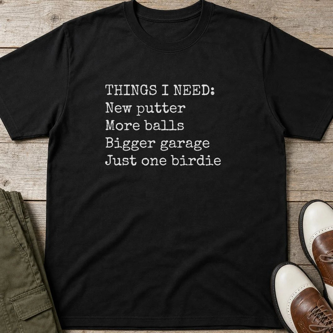 Things I Need T-Shirt in Black lying on a plain floor. T-shirt is a unisex cut and 100 per cent cotton.