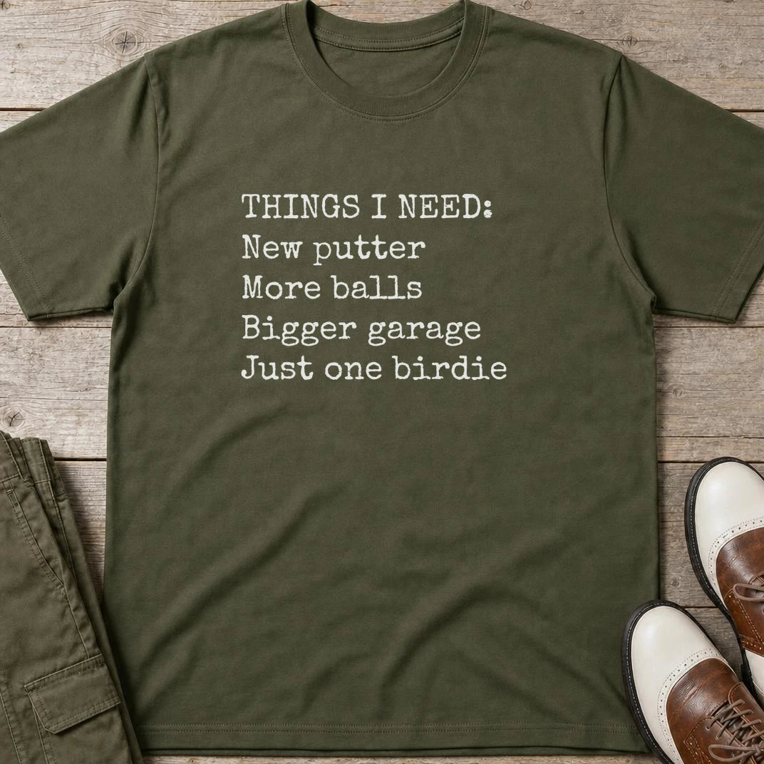 Things I Need T-Shirt in Military Green lying on a plain floor. T-shirt is a unisex cut and 100 per cent cotton.