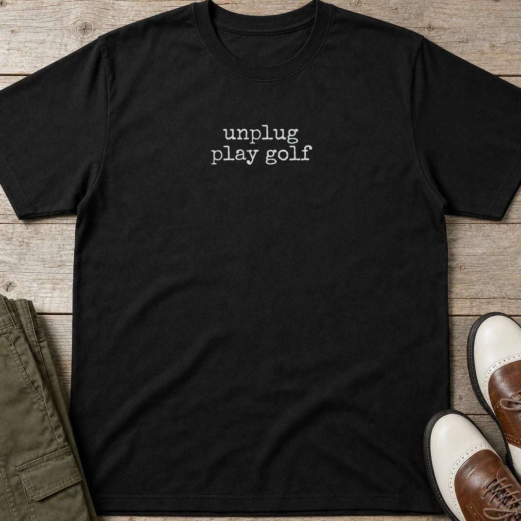 Unplug T-Shirt in Black lying on a plain floor. T-shirt is a unisex cut and 100 per cent cotton.