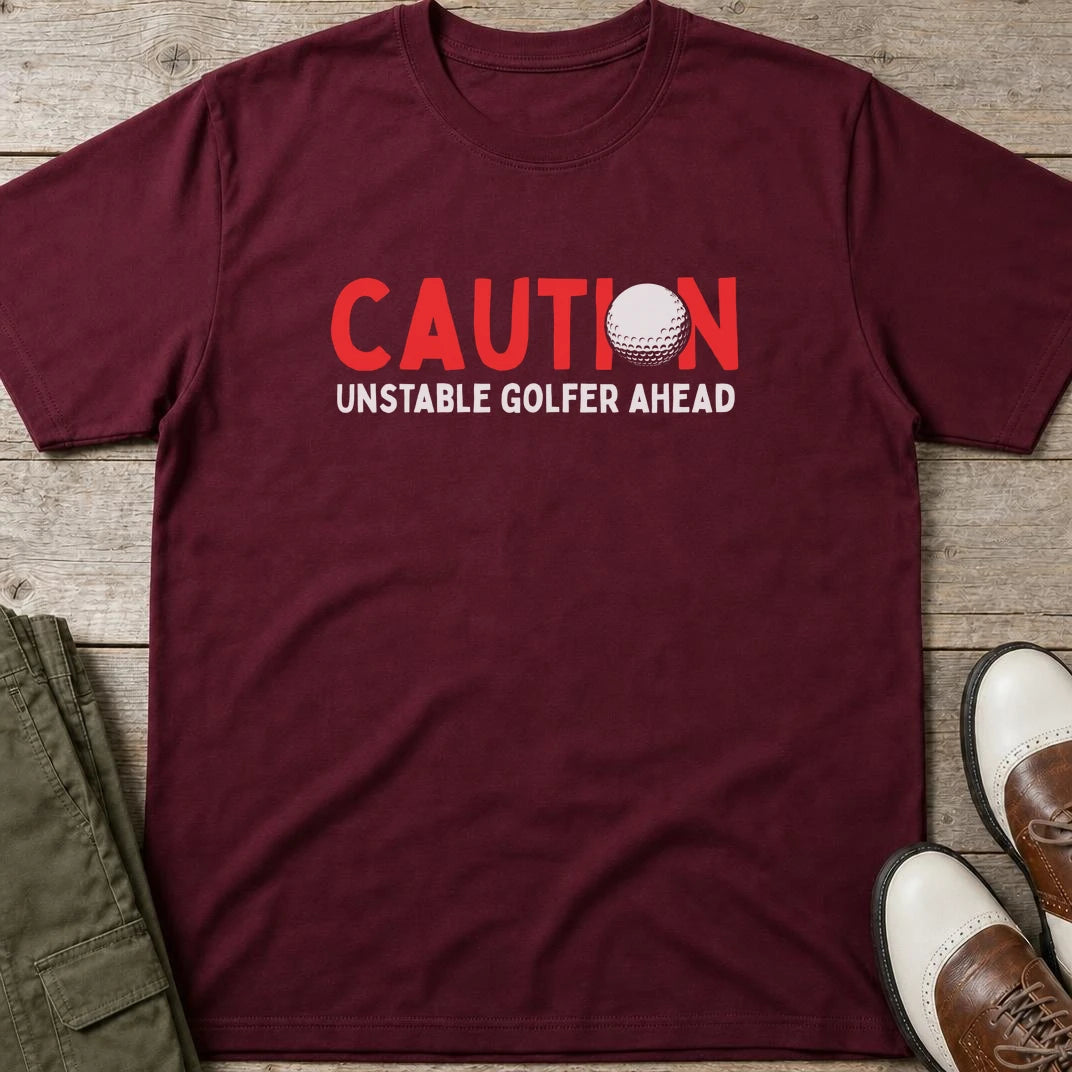 Unstable Golfer T-Shirt in Maroon lying on a plain floor. T-shirt is a unisex cut and 100 per cent cotton.