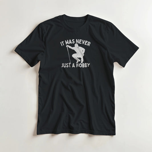 Just A Hobby T-Shirt in Black lying on a plain floor. T-shirt is a unisex cut and 100 per cent cotton.
