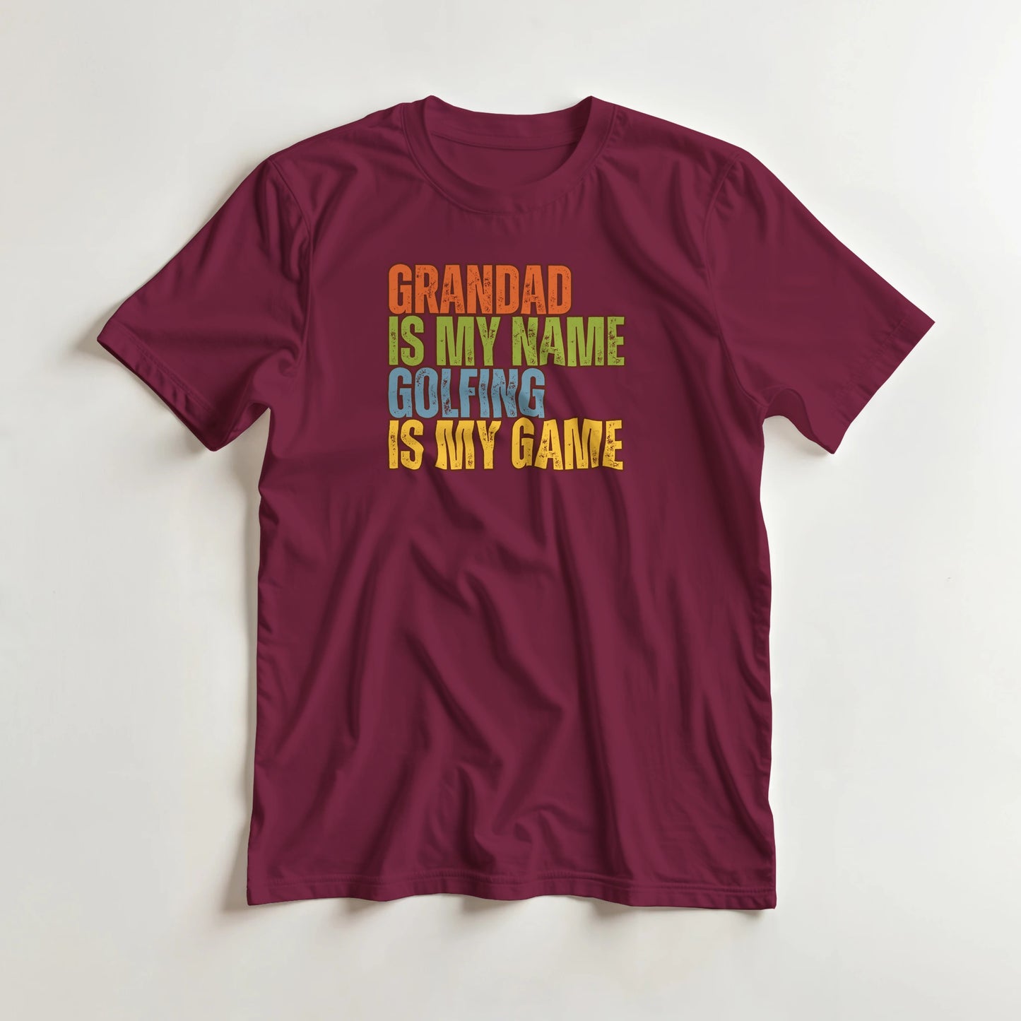 Grandad Golfing T-Shirt in Maroon XL lying on a plain floor. T-shirt is a unisex cut and 100 per cent cotton.