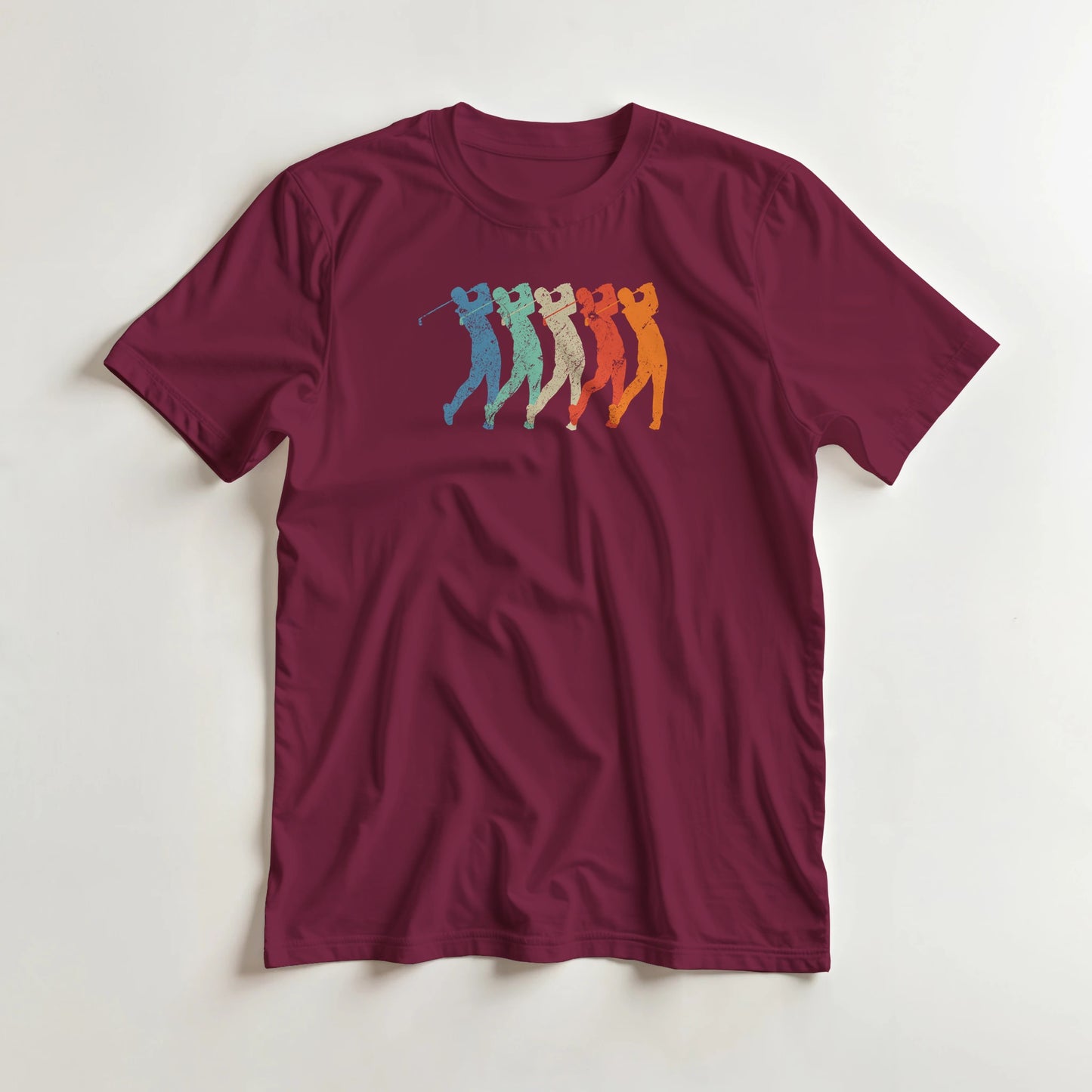 Golf Swing T-Shirt in Maroon lying on a plain floor. T-shirt is a unisex cut and 100 per cent cotton.