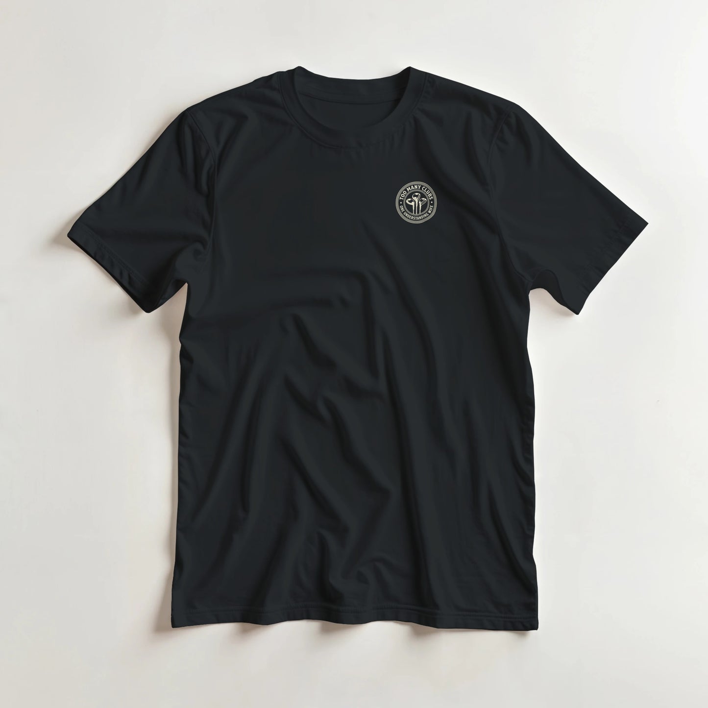 Too Many Clubs Pocket T-Shirt in Black lying on a plain floor. T-shirt is a unisex cut and 100 per cent cotton.