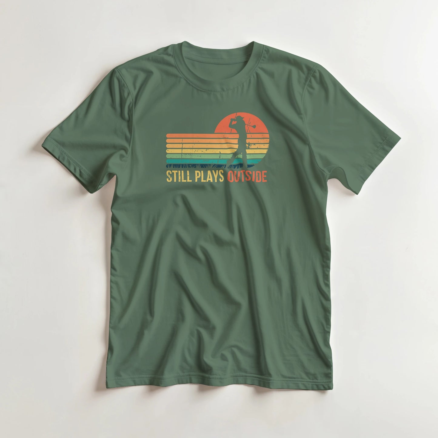 Plays Outside T-Shirt in Military Green S lying on a plain floor. T-shirt is a unisex cut and 100 per cent cotton.
